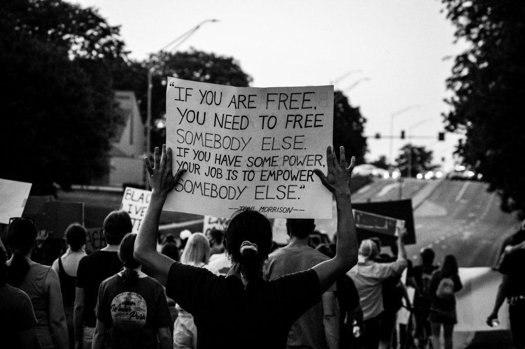 Person holding a sign promoting Workplace culture, equality, respect, transformational leadership trainings